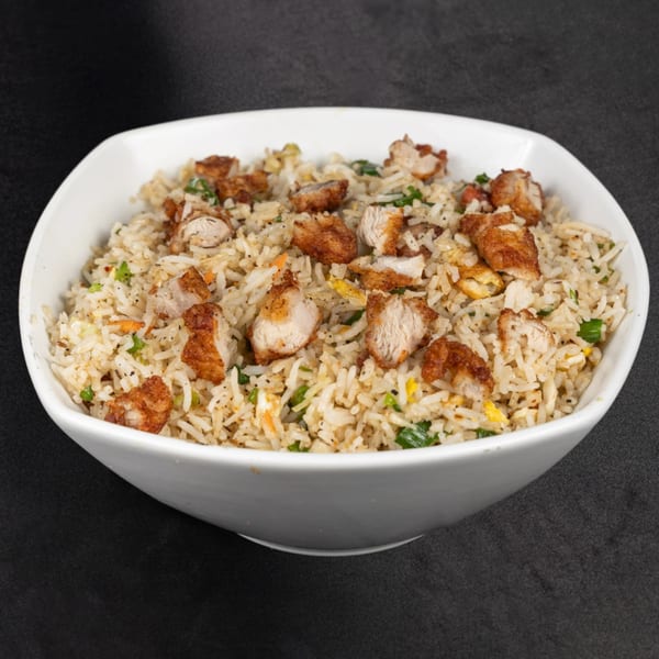 A white bowl filled with chicken fried rice, garnished with green onions, from Rotate Social.